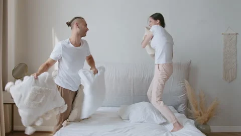 Young Funny Couple In Underwear Fighting With Pillows In The Bed