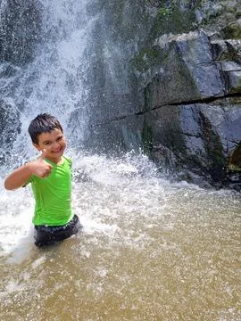 Happy kid bathing in a waterfall Stock Photos