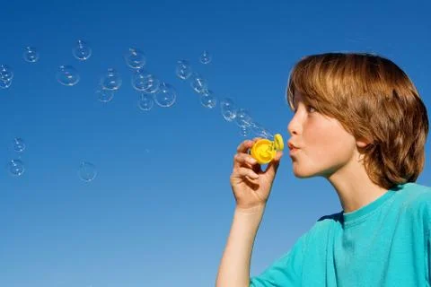 Happy kid blowing bubbles with bubble wand Stock Photos