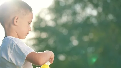 Happy kid blows bubble in park. Joyful child playing with bubbles outdoors. Kid 库存影片 311622869