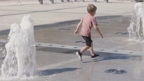 Happy kid boy playing at summer. Child play at the water fountain Видео 164226428