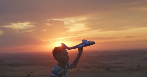 Happy kid close-up. Kid boy runs with toy plane at sunset. Silhouette of kid in Stock Footage 258168508