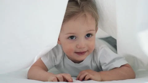 Happy kid crawling under the covers. Happy family. Kid crawling on bed under Video stock 154996706