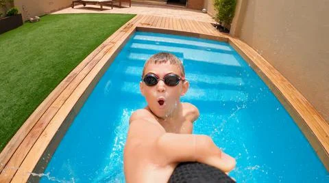 Happy kid filming himself while jumping into a pool with underwater camera. Stock Photos
