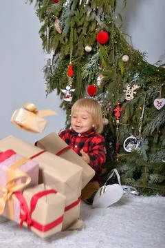 The happy kid is having fun with Christmas presents sitting on the background of Stock Photos