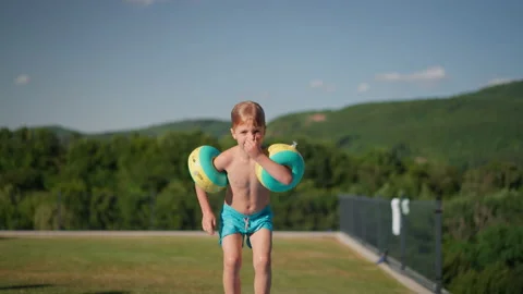 Happy kid having fun when jumping to swimming pool with inflatable armbands Stock Footage 204992671