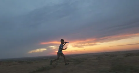 Happy kid. Kid boy runs with toy plane at sunset. Silhouette of kid in a meadow Stock Footage 258167602