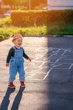 Happy kid laughs while playing hopscotch on the playground Stock Photos