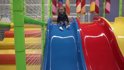 Happy kid moving down slide in children's play center Stock Footage 102268384