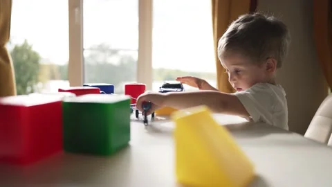 Happy kid is playing at table. Kindergarten education. Boy plays with colored Stock Footage 234390620