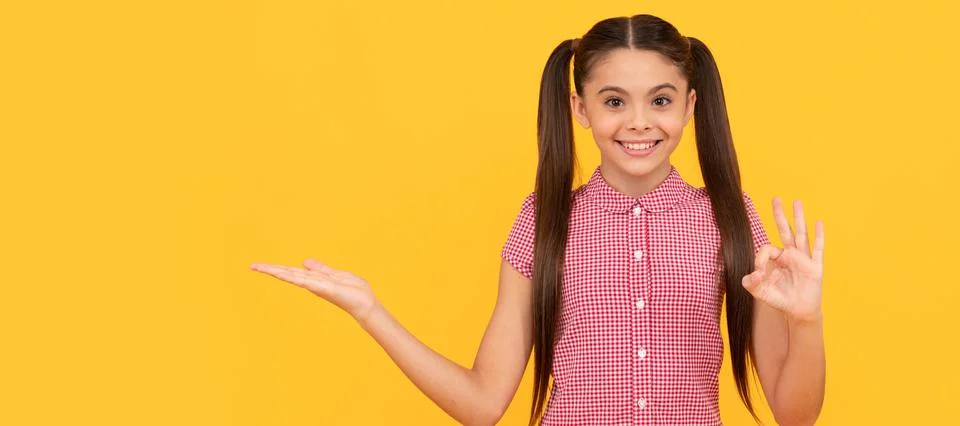 Happy kid presenting product on yellow background copy space show ok, advertise Stock Photos