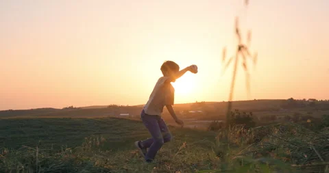 Happy kid running with a kite on a meadow in summer at sunset Stock Footage 240769387