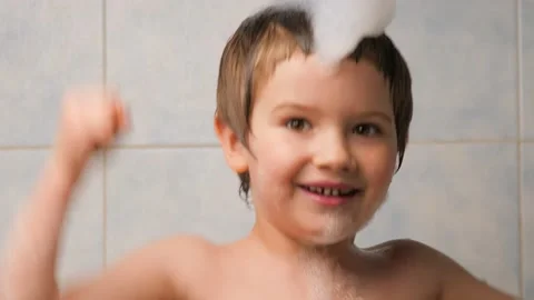 Happy kid taking a bubble bath. Boy playing with foam while bathing. Cute Stock Footage 131622986
