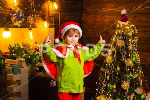 Happy kid wearing Santa Hat on Christmas tree background. Having an idea Stock Photos