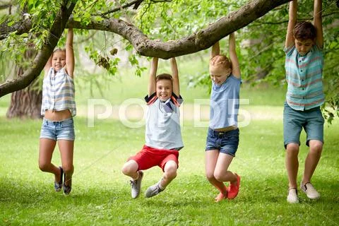Happy kids hanging on tree in summer park Stock Photos