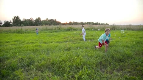 Happy kids playing with soap bubbles in field Video stock 88316686