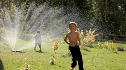 Happy kids playing in sprinkler Stock Footage