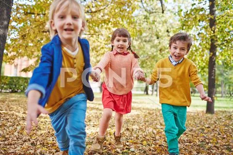 Happy kids running in park in autumn Stock Photos