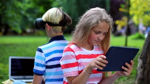 Happy kids using VR glasses outdoor searching online on tablet in summer green 스톡 동영상 138003305