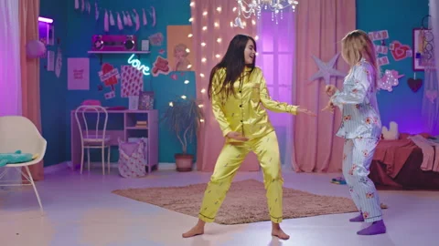 Happy ladies dancing in front of the camera in pajamas in the bedroom they have Stock Footage 136097912
