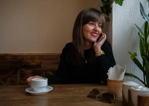 The happy lady is talking on a mobile cell phone in a cafe Stock Photos