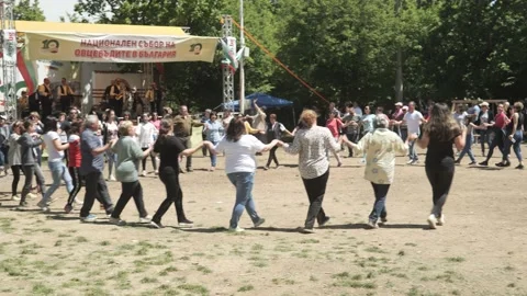 Happy large crowd dancing Bulgarian traditional horo at sunny festival Stock Footage 193370678