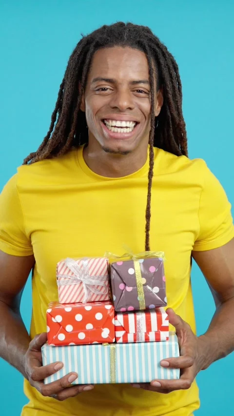 Happy latin man with dreadlocks holding many colorful gifts Stock Footage 256563728