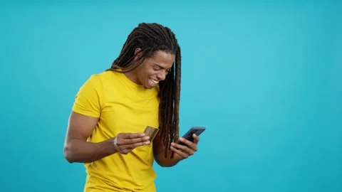 Happy latin man using mobile and card to shopping online Stock Footage 241190208