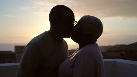 Happy Latin senior couple having moment kissing on rooftop during sunset Stock Footage