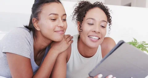 Happy lesbian couple lying on bed using tablet, in slow motion Stock Footage 340968392
