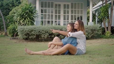 Happy lesbian couple sitting on the grass on backyard of their house 動画素材 108381353