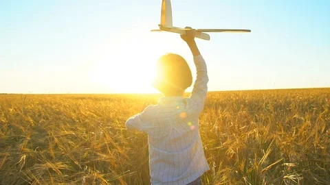 Happy little boy child running with toy airplane in wheat field at sunset. Kid Stock Footage