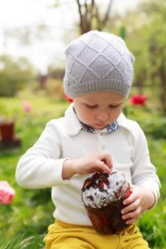 Happy little boy eats Easter Cake, in spring garden, outside. Cute happy litt Stock Photos