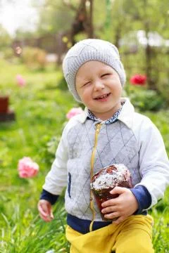 Happy little boy eats Easter Cake, in spring garden, outside. Cute happy litt Stock Photos
