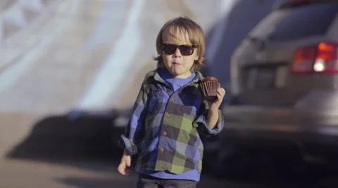 Happy Little Boy Eats His Cupcake In A Parking Lot, On The Way To His Family Car Stock Footage 49186079