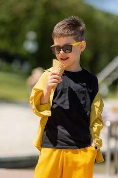 Happy little boy eats ice cream in a waffle cone in summer on a walk Stock Photos