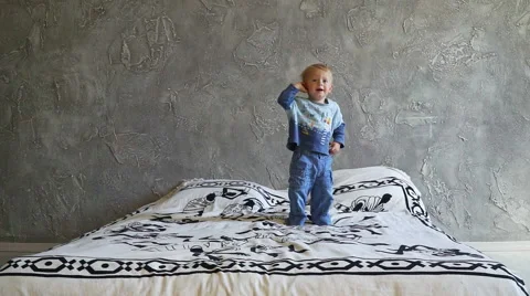 Happy little boy jumping on the bed and accidentally flips Stock Footage 69020752