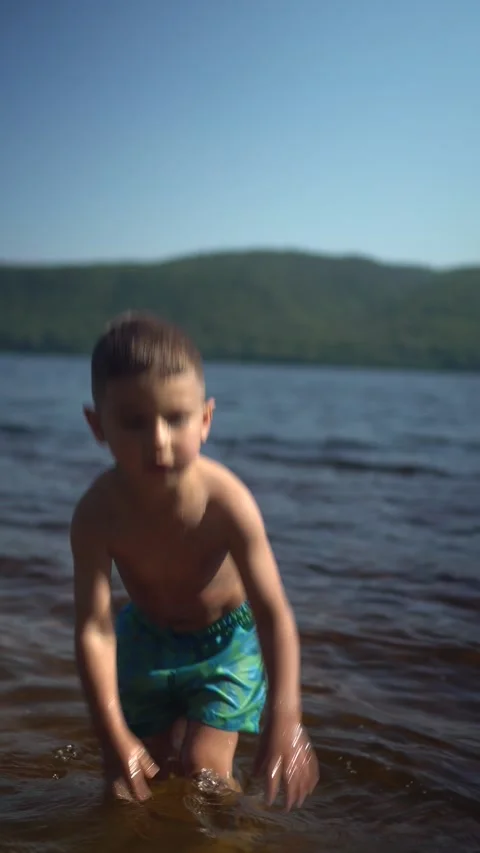 Happy Little Boy Playing in River Water During Summer Vacation. Vertical Video 스톡 동영상 343894572