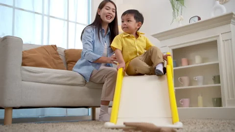 Happy little boy sliding down with laughter while his mother watches nearby 스톡 동영상 339582567