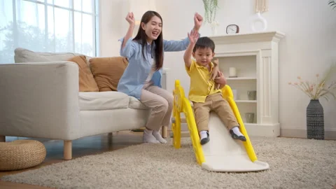 Happy little boy sliding down with laughter while his mother Stock Footage 339582608