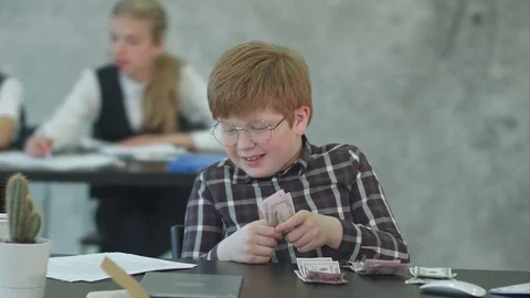 Happy little boy at the table counts money Stock Footage 77733835