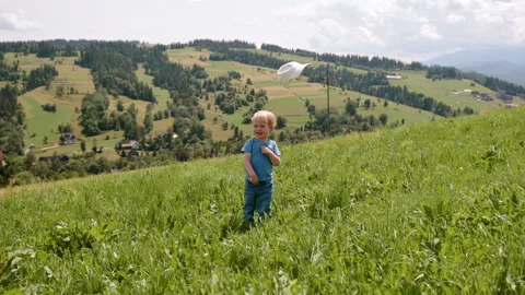 Happy Little Boy Throwing Cap in the Air and Laughing with Mountain Background Stock Footage 307241946
