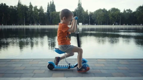 Happy little boy two years old, riding a scooter in a summer park Stock Footage 92093353