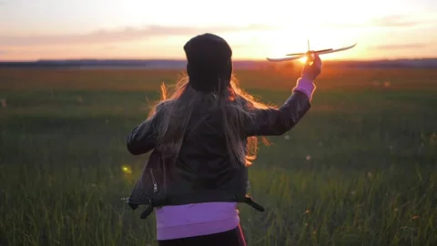 Happy little girl child runs at sunset on the meadow with a toy plane. Wants to Stock Footage