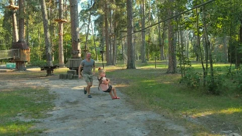Happy little girl is moving on the ropeway in rope park Stock Footage