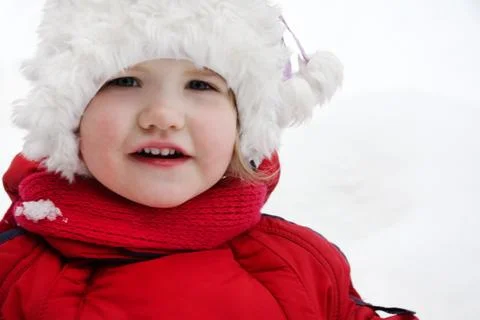 Happy little girl wearing warm clothing stands and looks at camera Stock Photos