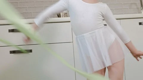 A happy little girl in a white gymnastic swimsuit trains, dances with a ribbon Vídeo Stock 102919267