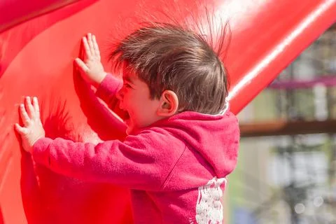 Happy little kid having fun playing outdoors in the playground. Stock Photos