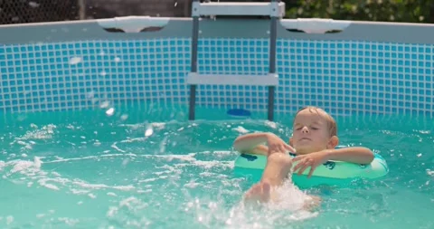 Happy little kid with inflatable ring playing in pool, laughing and splashing Stock Footage 260337332