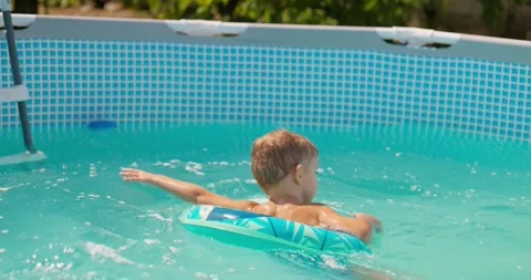 Happy little kid with inflatable ring playing in pool, laughing and splashing Stock Footage 260486039